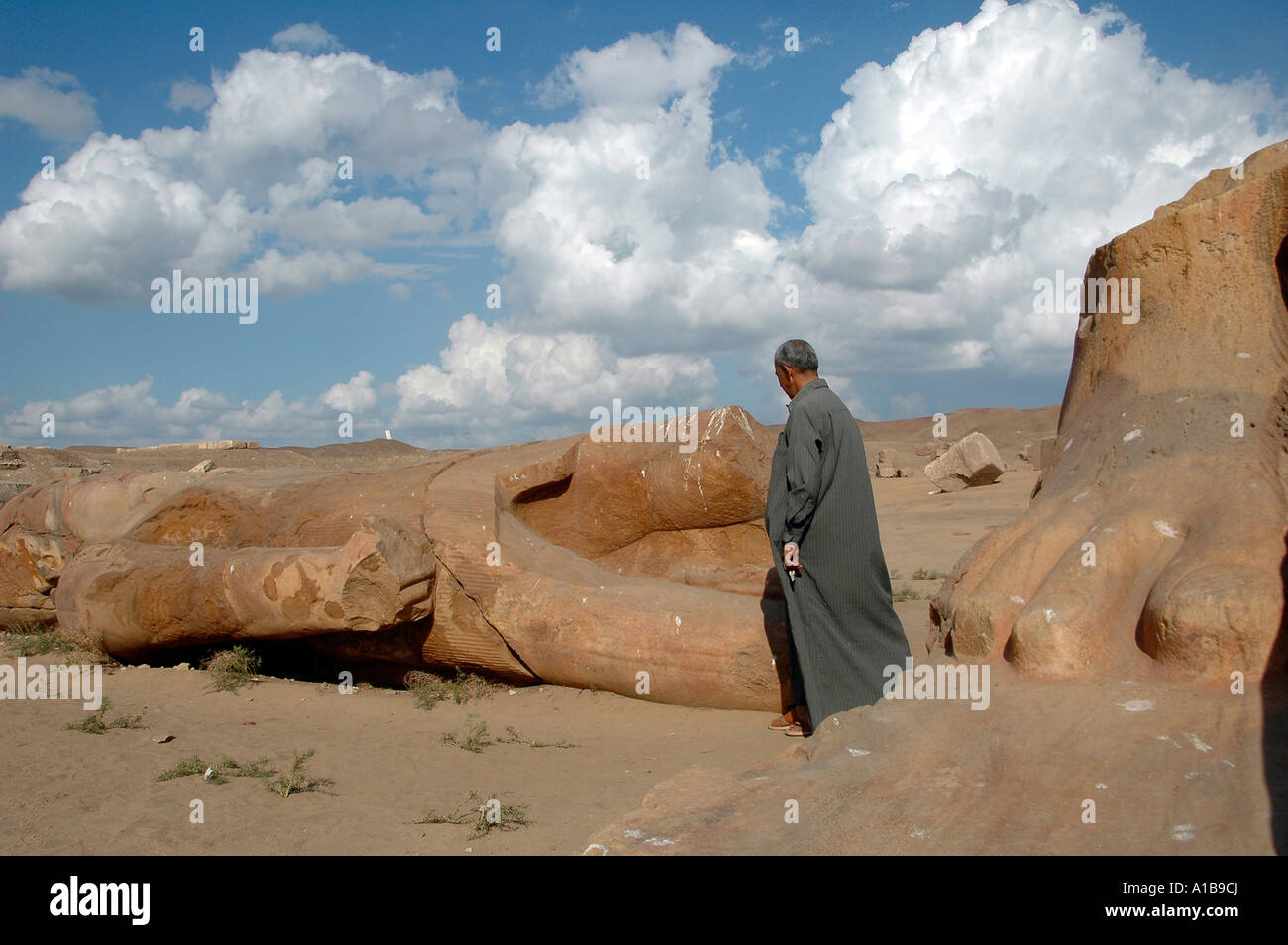 An Egyptian man stands by sculptural fragments, recovered from the excavations at the ancient temple site of Tanis in eastern Nile river delta Egypt Stock Photo