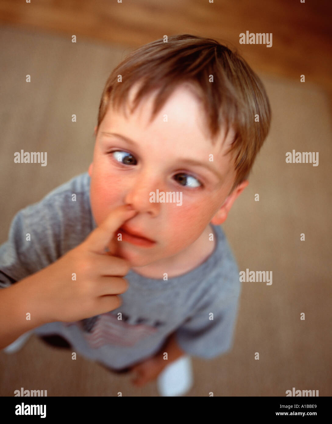 child making a cross eyed face while playing with nose Stock Photo