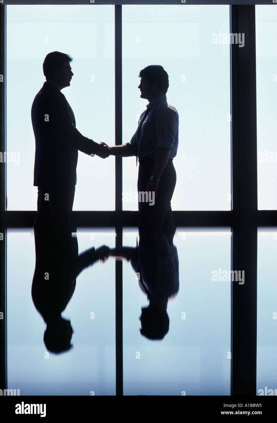 Two Executives with Opposing Views Shaking Hands and Closing the Deal Stock Photo