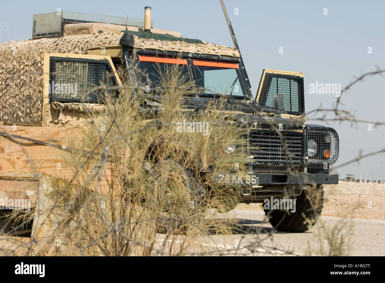 Static british military land rover behind razor wire and undergrowth ...