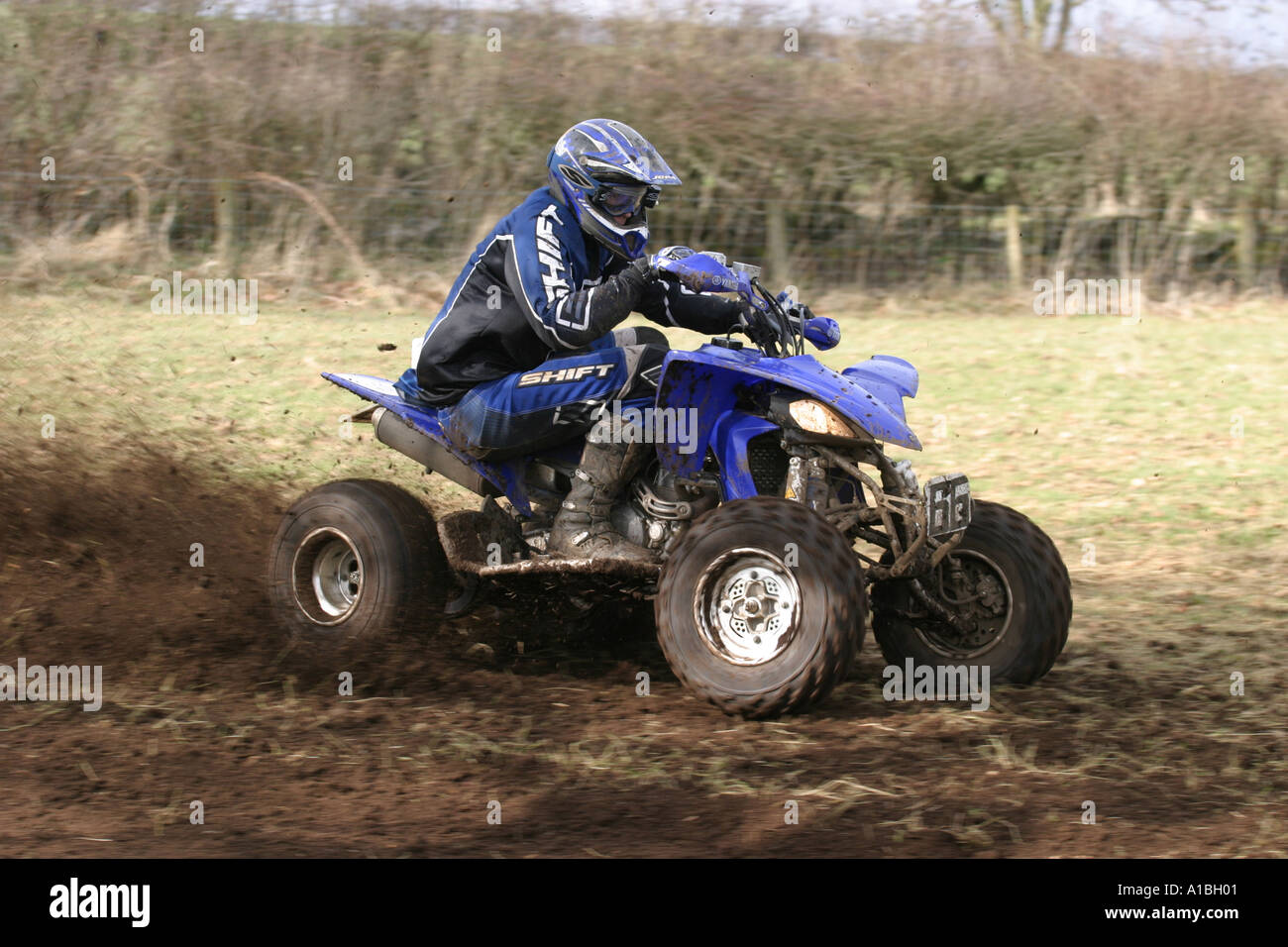 Quad Racer in action on blue quad bike spraying mud behind outside