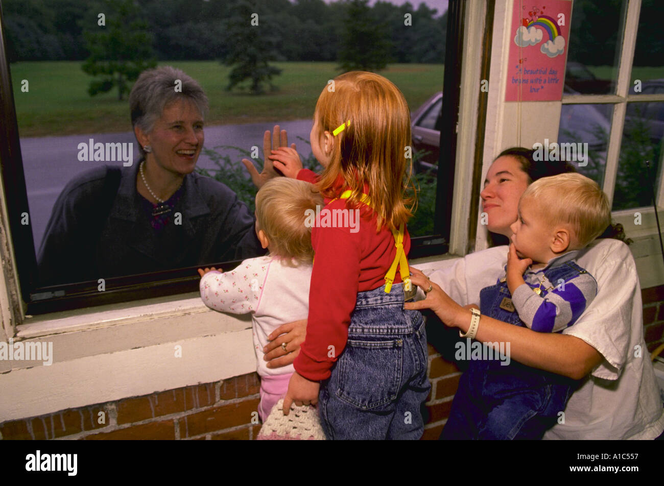 Children say good bye to parents through a window at a private day care center in Providence Rhode Island Stock Photo