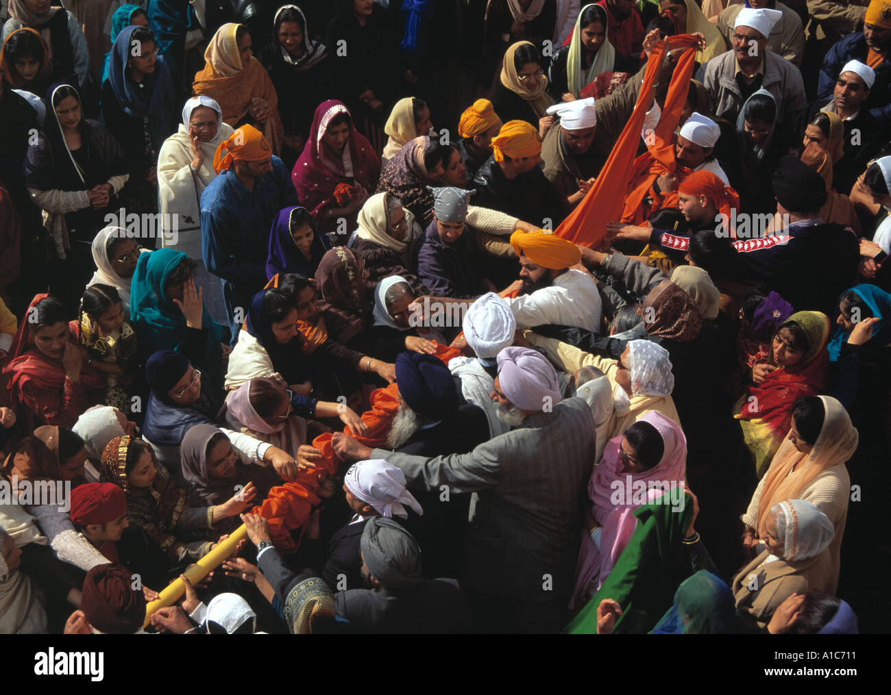 Crowd of Sikhs changing the cover on the pole that hold the Nishan Sahib, Sikh flag, Vaisakhi, New Year. Stock Photo