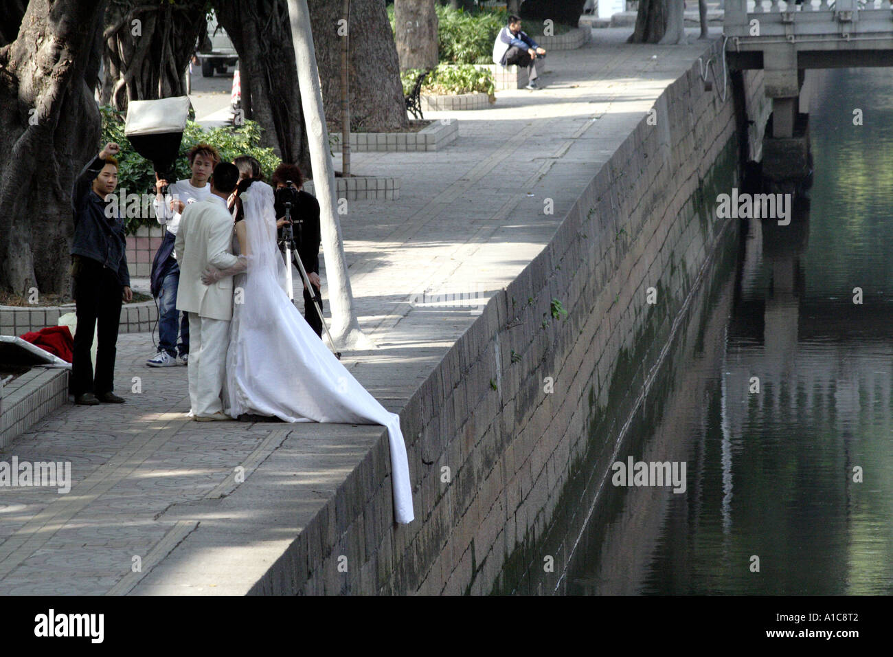 A Chinese couple on Shamian Island in Guangzhou, China poses for their wedding pictures along the waters surrounding the island. Stock Photo