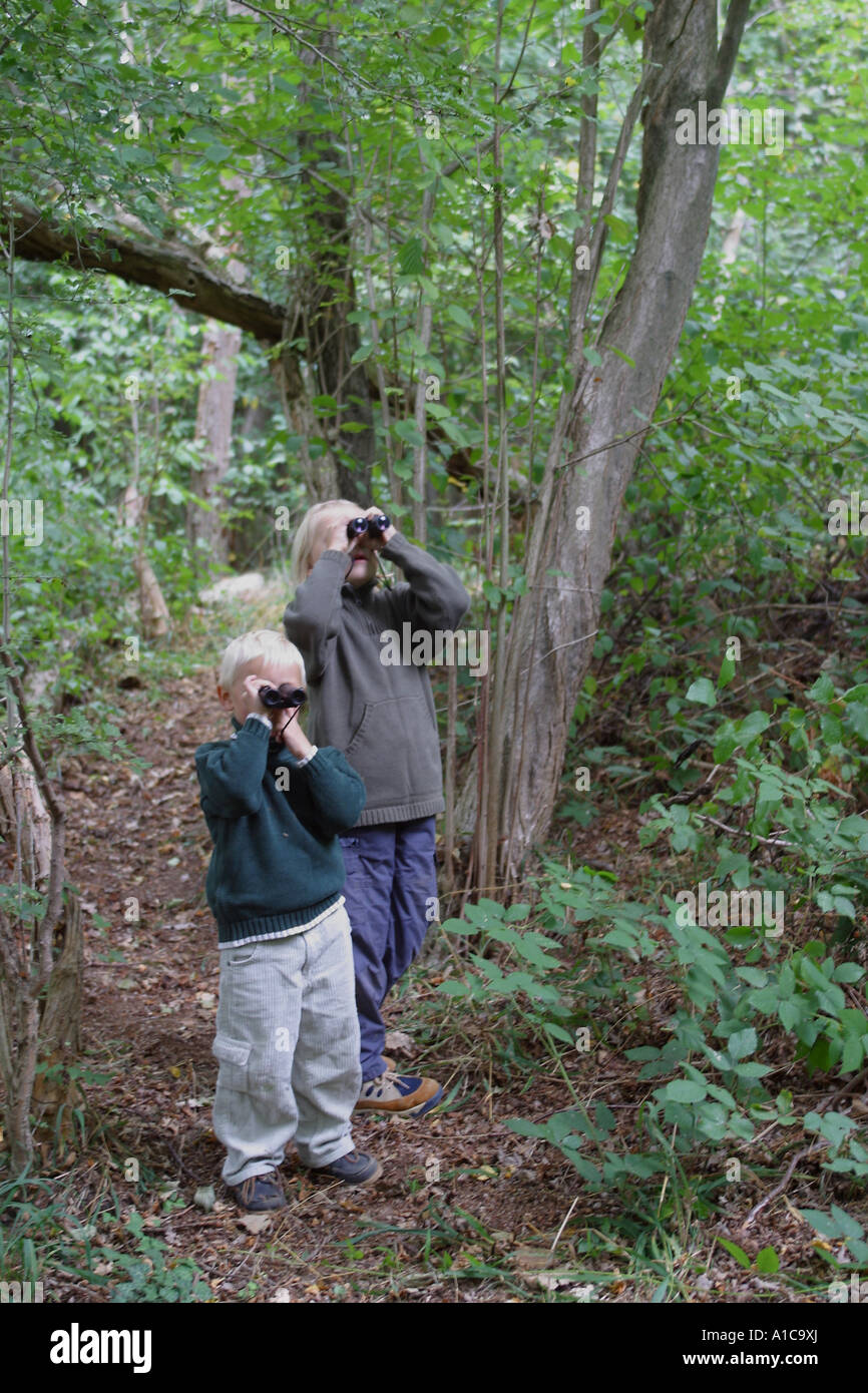 girl  and boy discovering the forest with binoculars Stock Photo