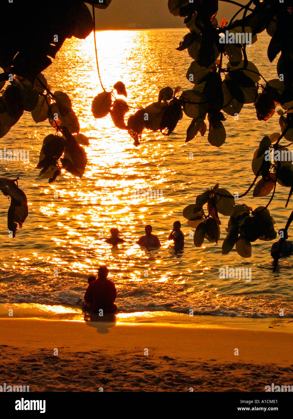 Holidaymakers bathing at sunset Teluk Nipah beach Pulau Pangkor island Stock Photo