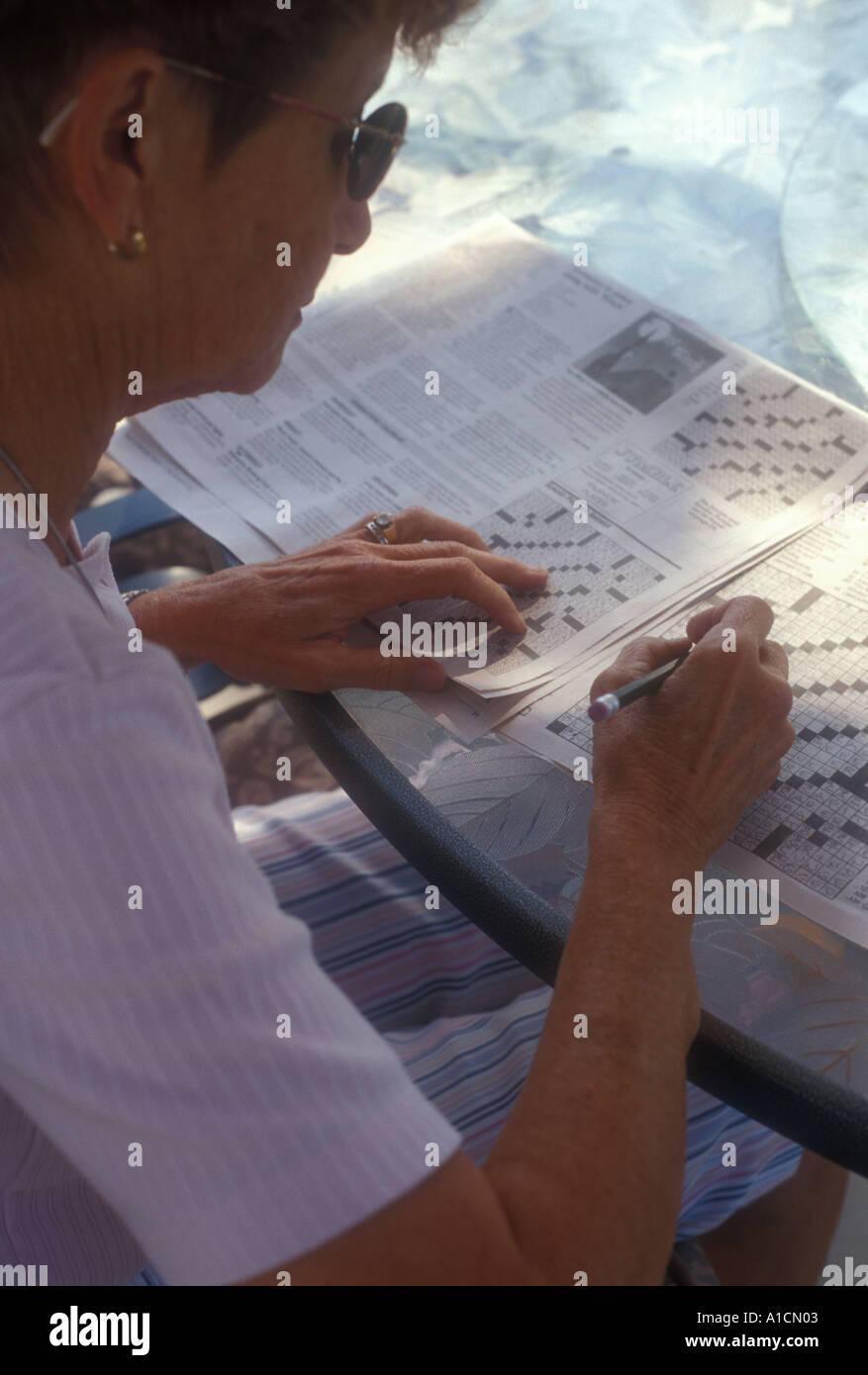 Working crossword puzzle outside outdoors summer day hires stock