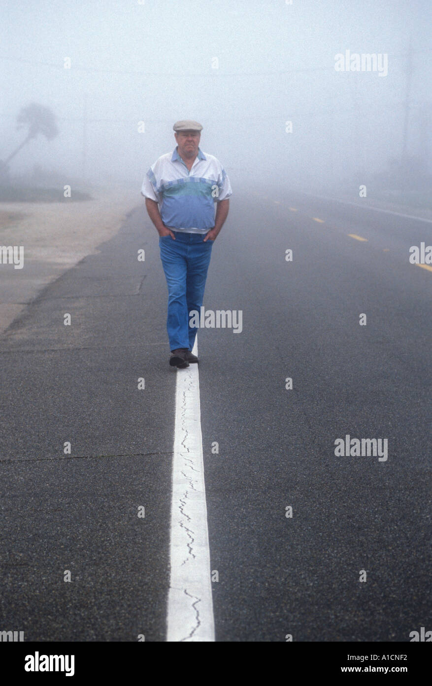 Man walking white line along Foggy Street Stock Photo
