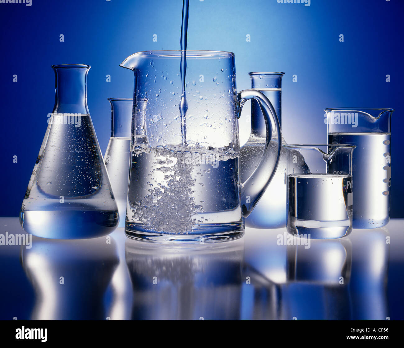 CLEAN PURE WATER POURING IN TO GLASS JUG WITH FLASKS BEAKERS OF WATER