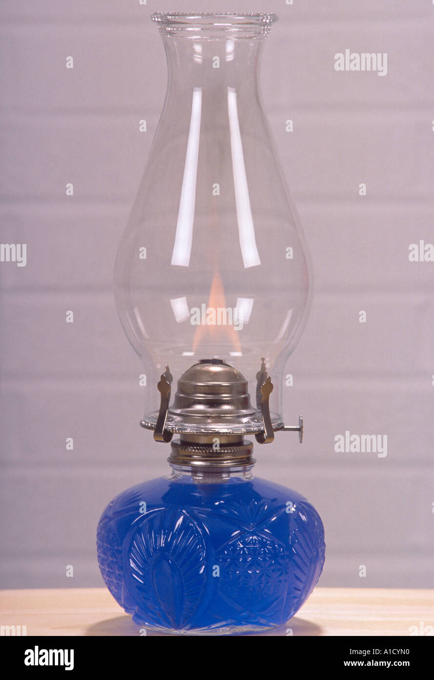 glass oil lamp with flame and blue oil in cut glass base white brick