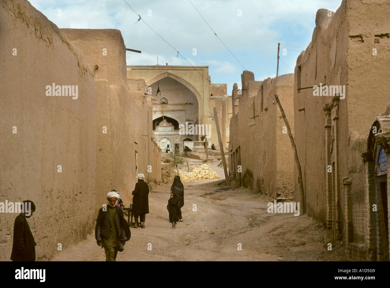 back street mud wall walled road man men going to mosk turban house urban village suburb residential area transport Stock Photo