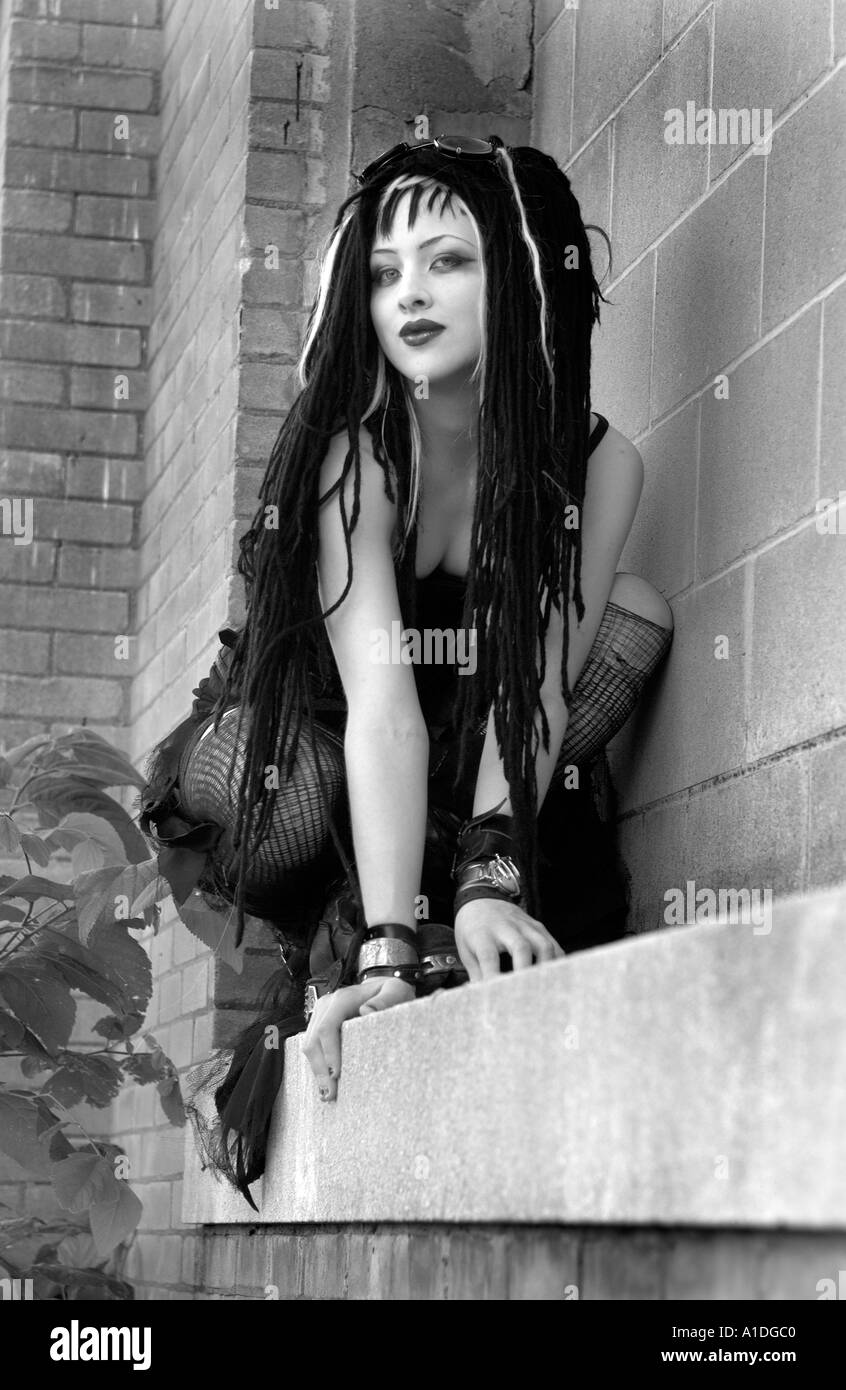 Goth girl crouching on ledge Stock Photo