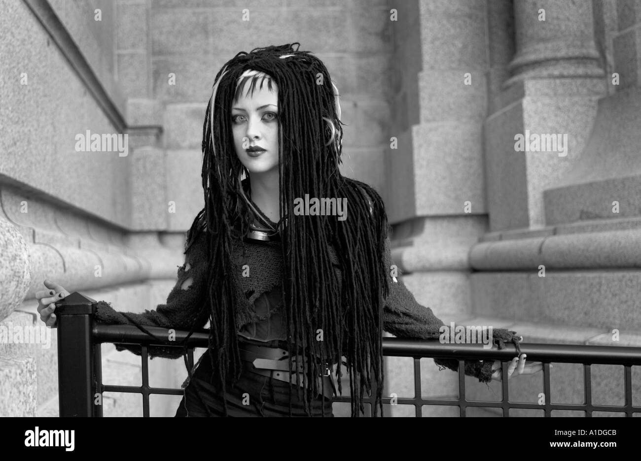 Goth girl in black standing at railing Stock Photo