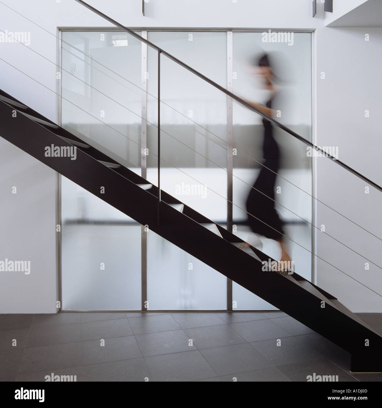Blurred figure walking up modern metal staircase Stock Photo