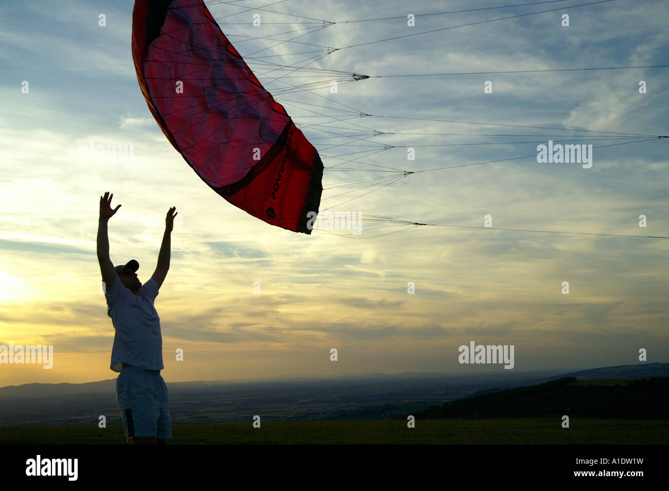 Man teenage boy starting parachute powerkite kite on meadow hill over