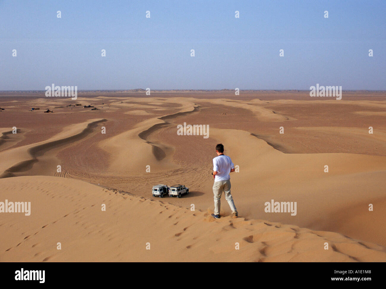 Young man walks down the sand dunes in the Sahara Desert Morocco Stock Photo