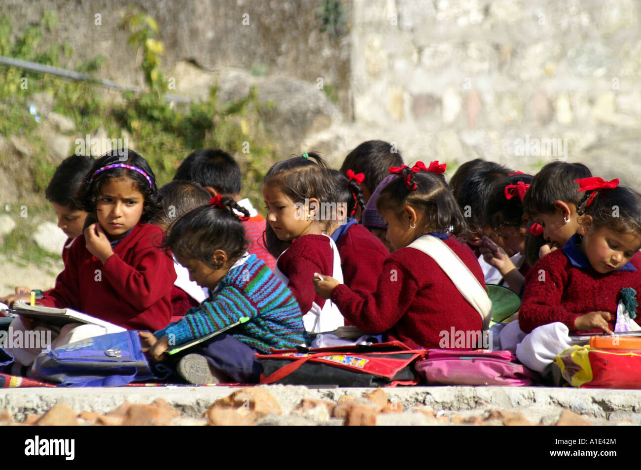 Group of young children schoolboys schoolgirls indian kids sitting writting exam outdoors school yard, Bhagsunag, India Stock Photo