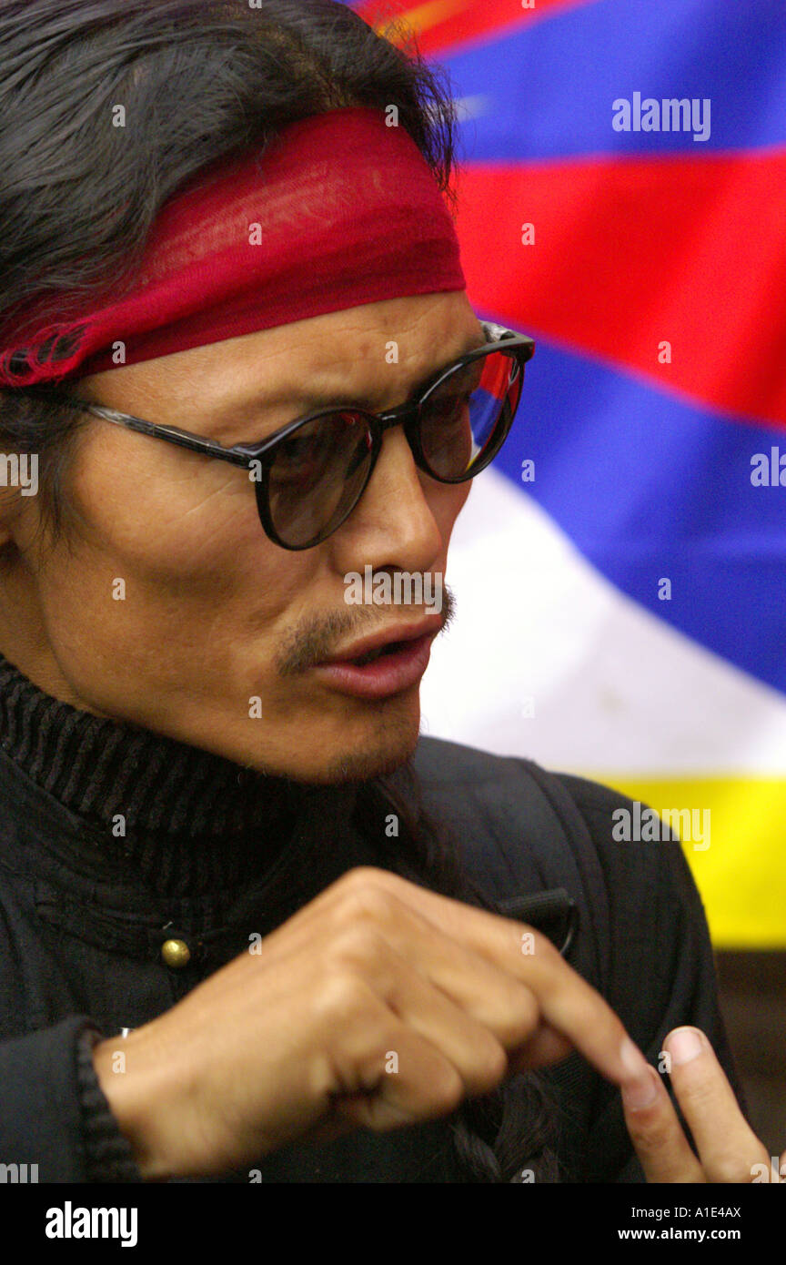 Portrait of tibetan Tenzin Tsundue political activist discussing politically sensitive issue on background of tibetan flag Stock Photo