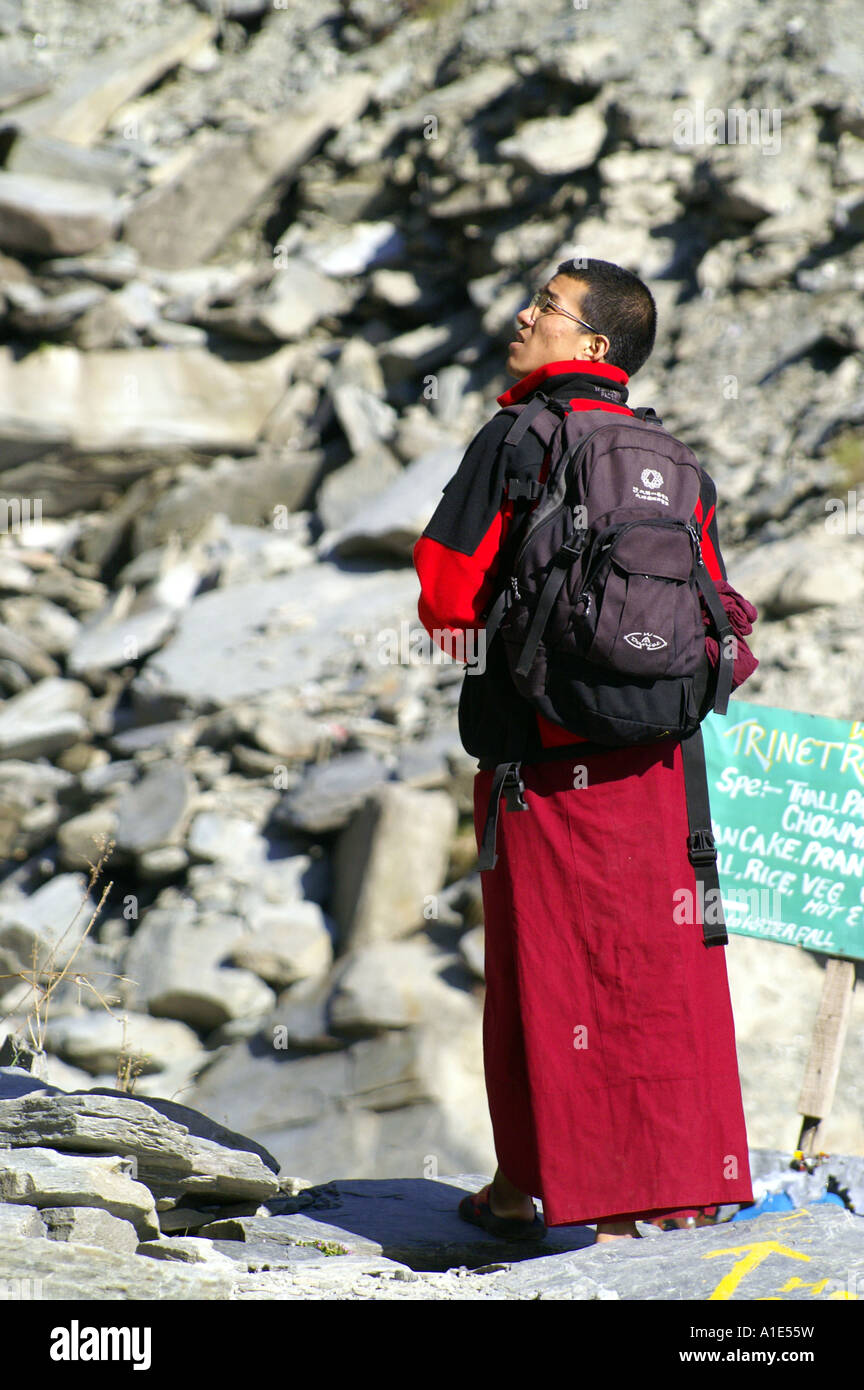 Buddhist tibetan monk with backpack trekking at boulder rocky surface