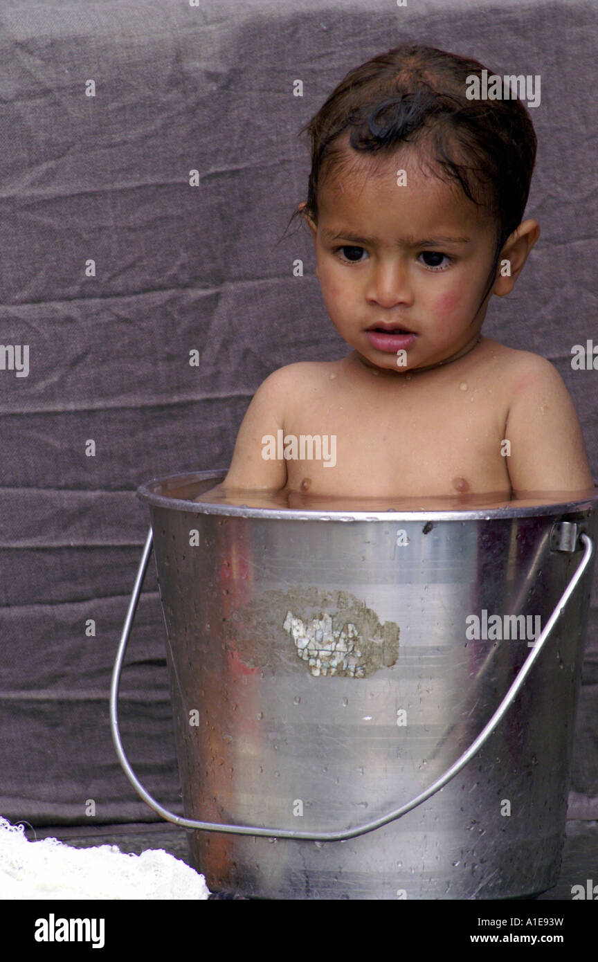Small broody child kid indian boy enjoying bath in tight stainless ...