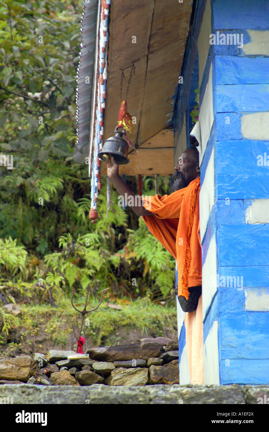 Old indian yogi sadhu holy man ringing ritual bell in Shiva temple at