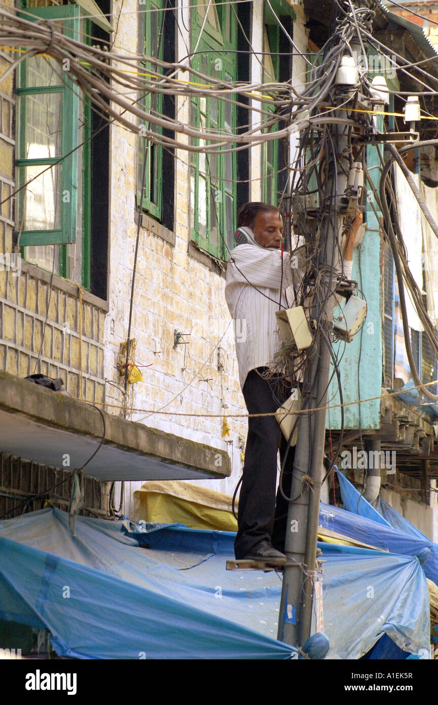 Indian expert technician repairing telephone lines standing on pole in McLeod Ganj