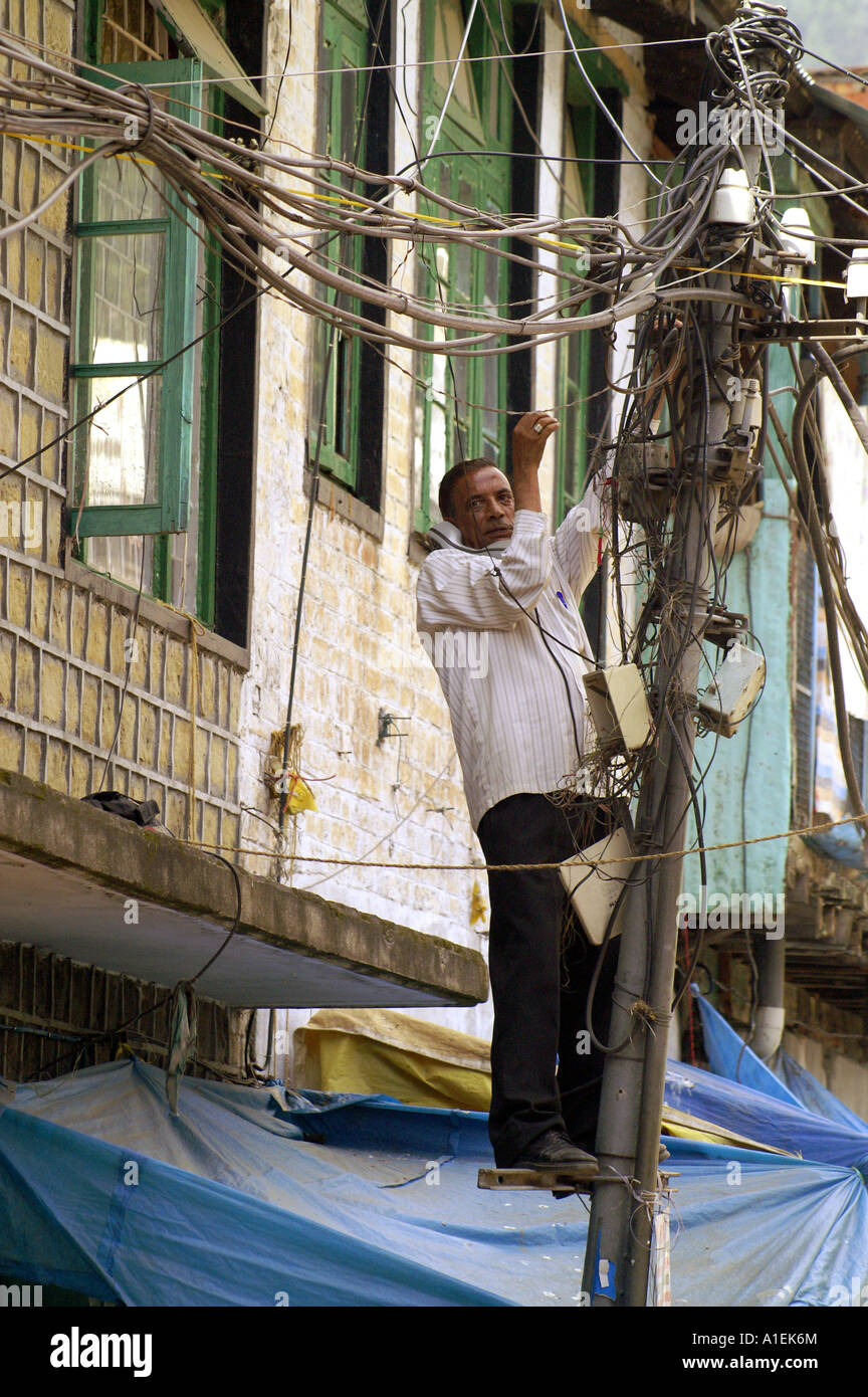 Indian expert technician repairing telephone lines standing on pole in McLeod Ganj
