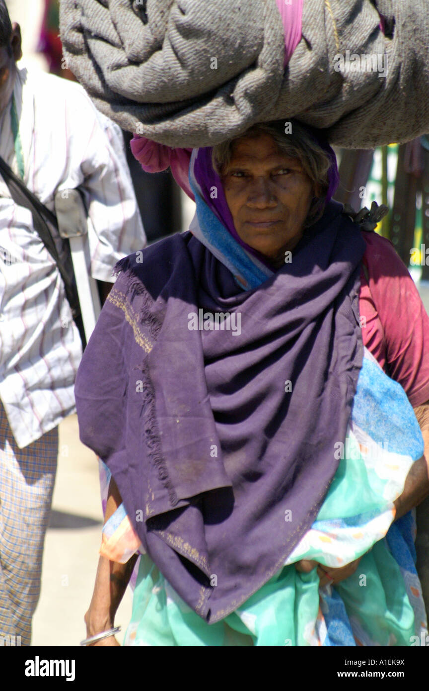 Old indian woman carrying heavy load of blankets on her head Stock Photo Alamy