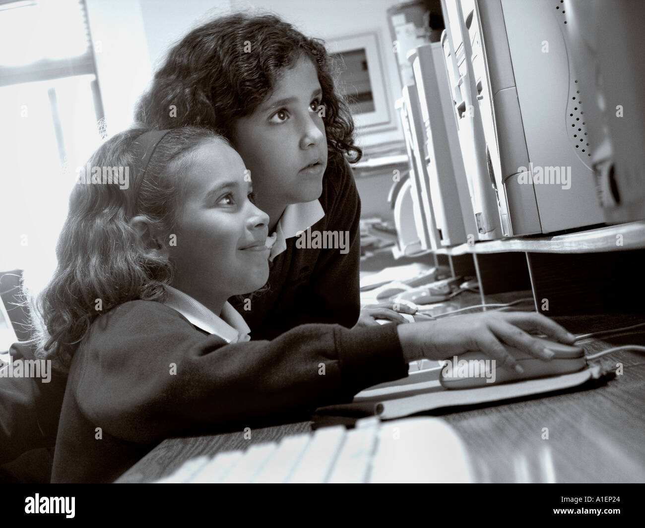 Two junior schoolgirls work together on their computer terminal in modern spacious school computer classroom Stock Photo