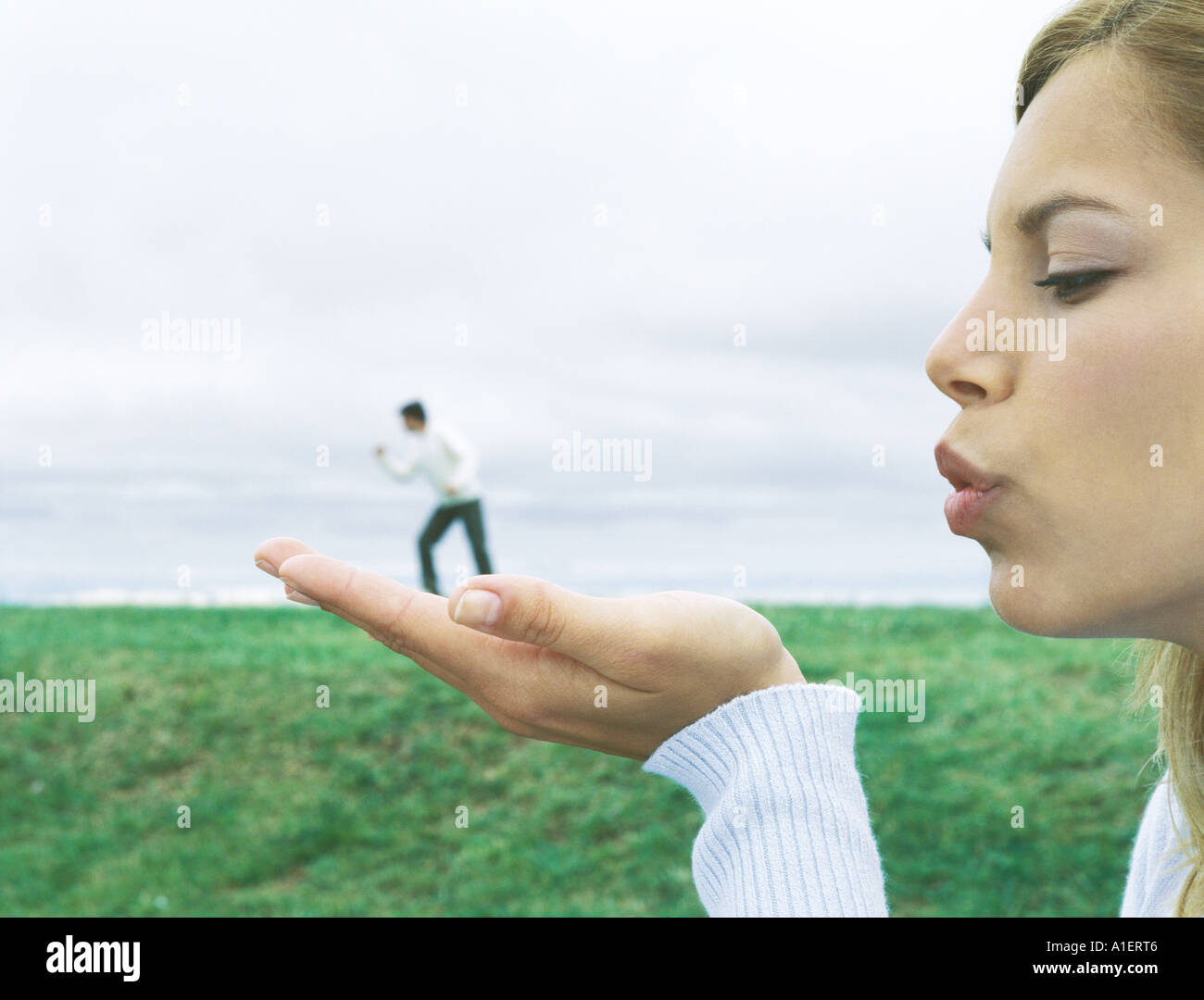 Man standing on woman's hand, optical illusion Stock Photo