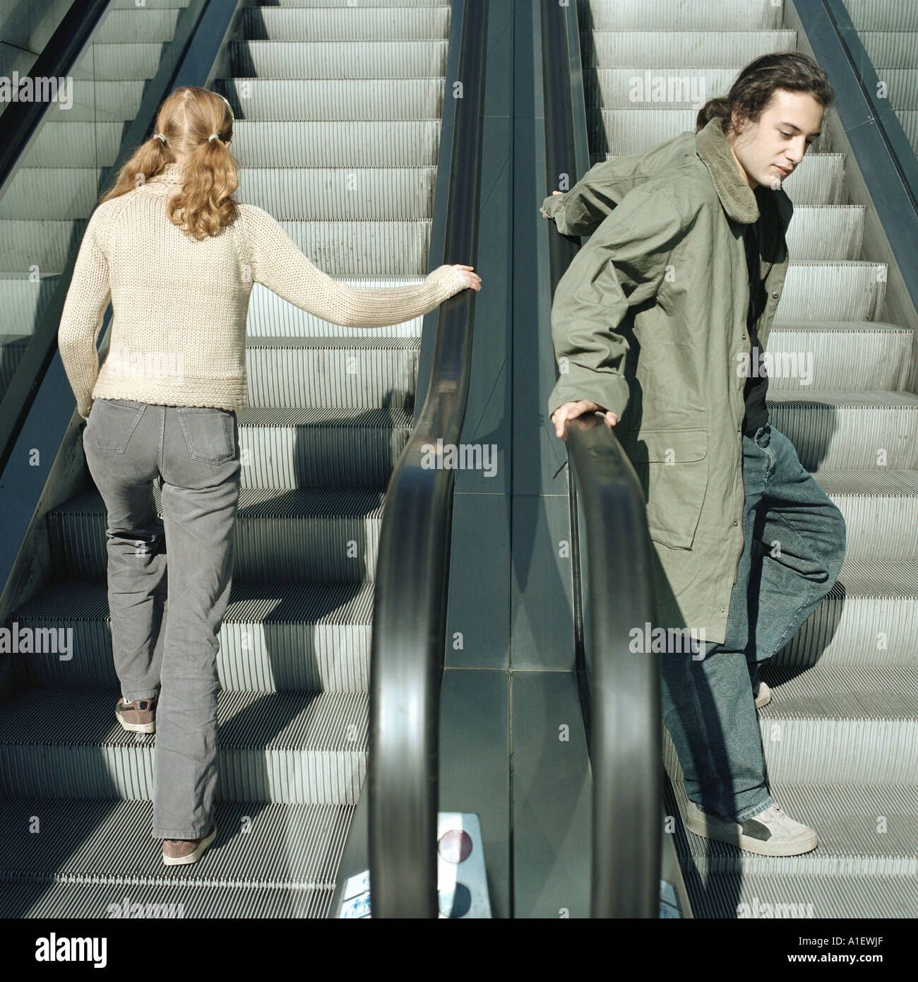 Young man and young woman on escalators Stock Photo