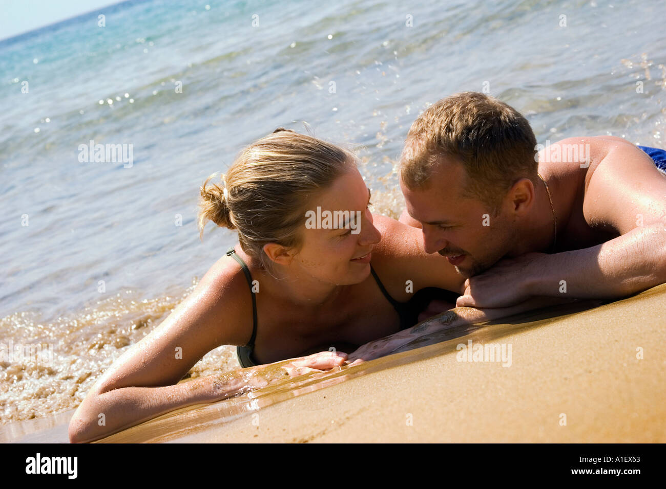 couple lying in the sand on a greek beach Stock Photo