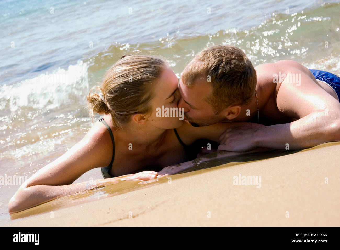 couple lying in the sand on a beach in Greece Stock Photo