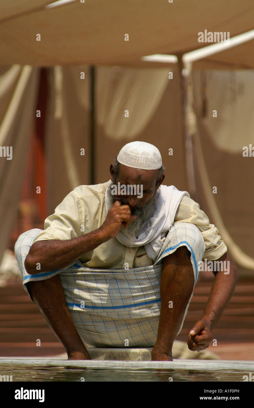 Old religious Muslim man performing ritual bath in Jama Masjid mosque