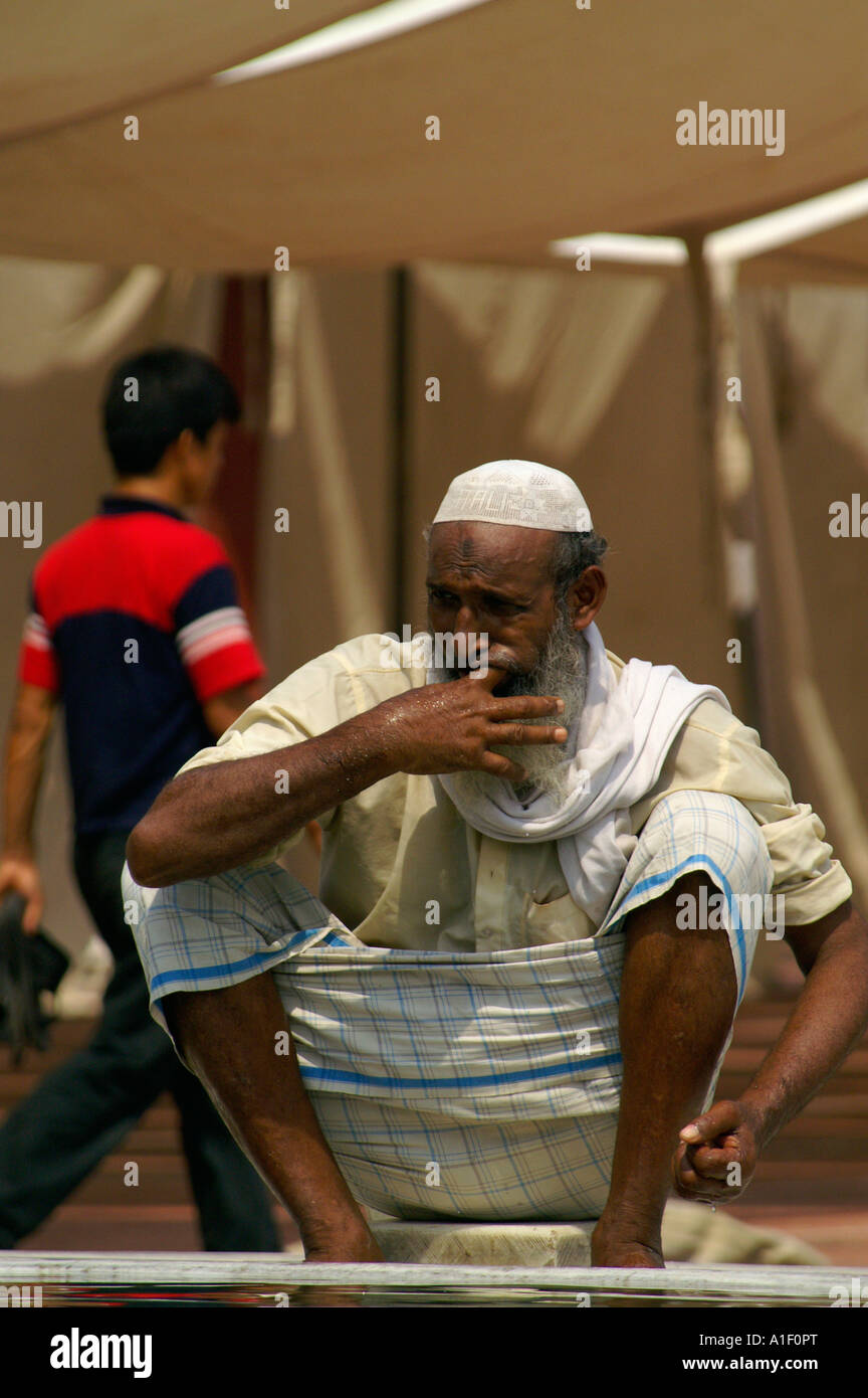 Old religious Muslim man performing ritual bath in Jama Masjid mosque