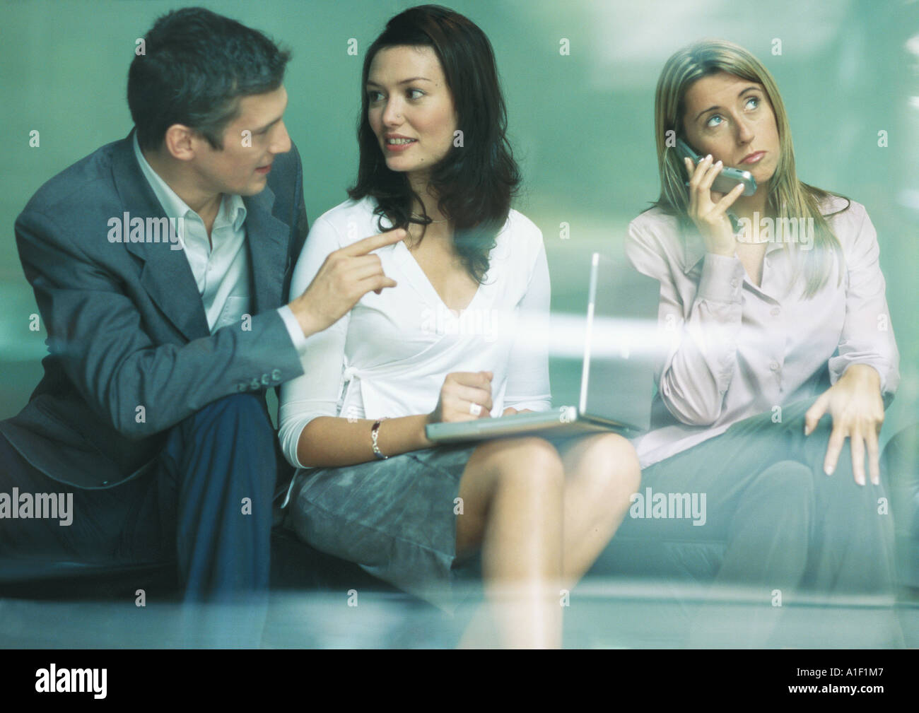 Three businesspeople using laptop and cell phone Stock Photo