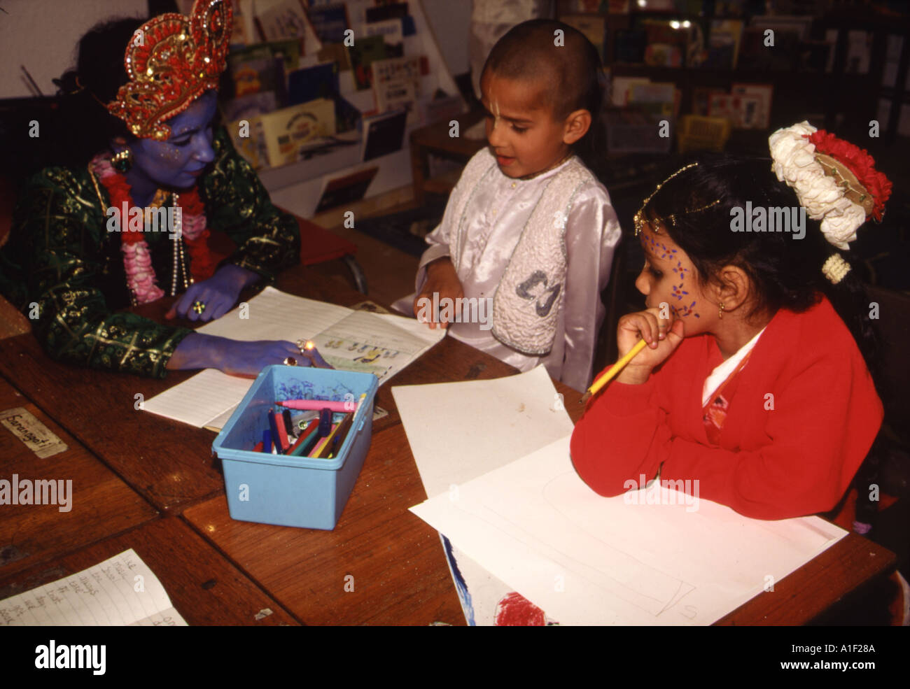 A teacher dressed and painted blue on the occasion of Lord Krishna's birthday with her pupils, Hindu school Watford, UK Stock Photo