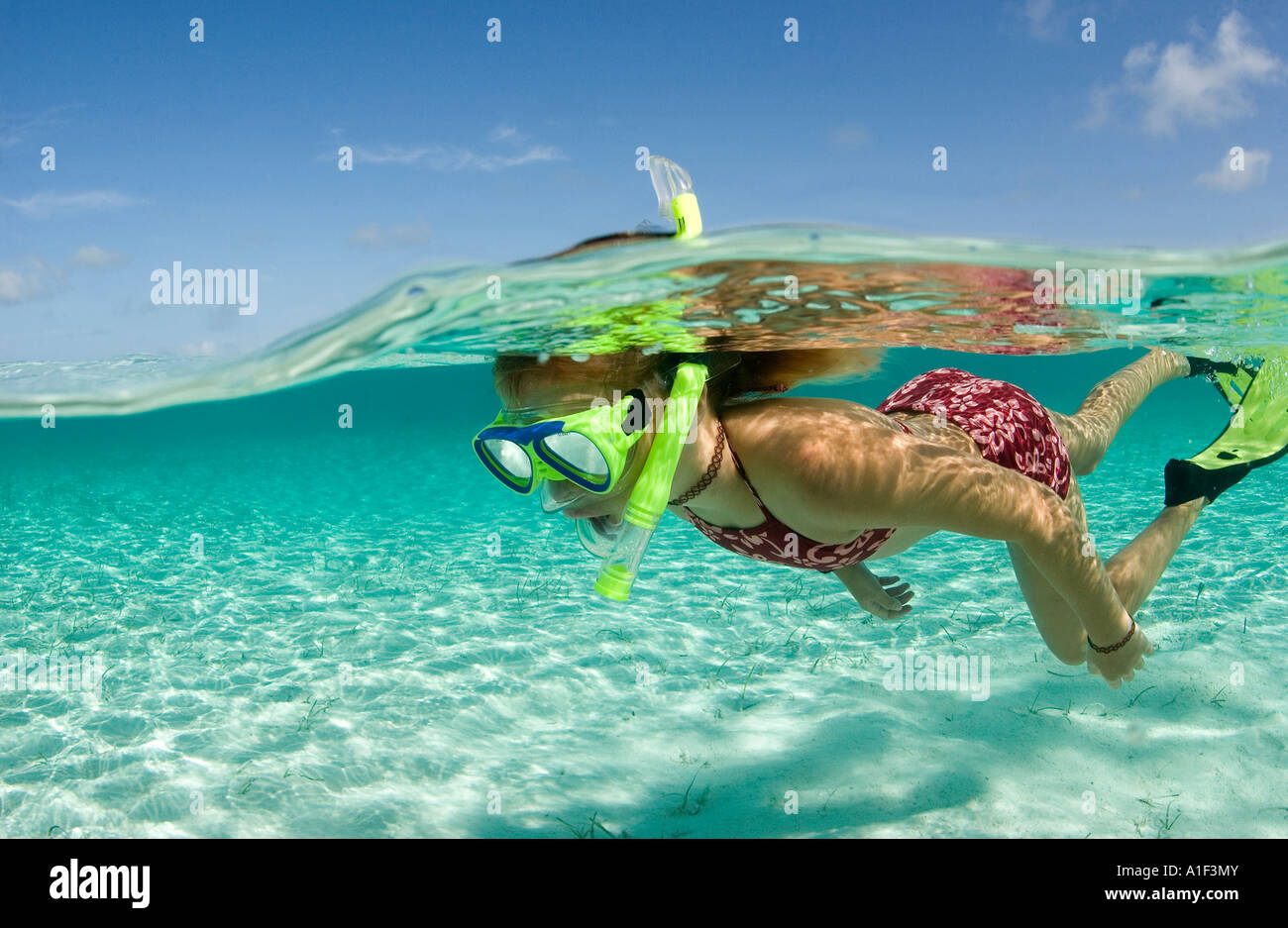 A YOUNG GIRL PROPELS HERSELF WHILE SNORKELING IN THE CLEAR WATERS OF THE EXUMA ISLAND CHAIN Stock Photo