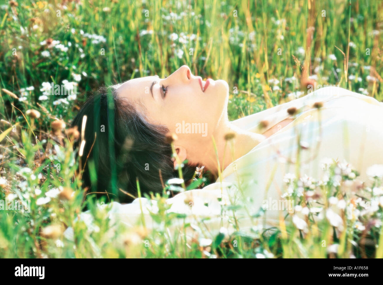 Woman lying in mountain meadow Stock Photo