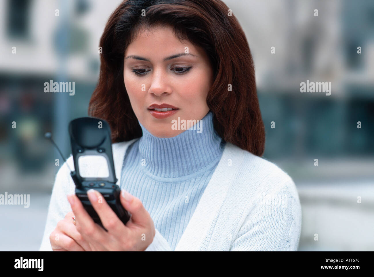 Woman dialing cell phone in street Stock Photo
