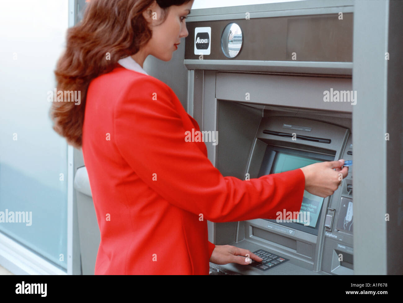 Businesswoman using cash machine Stock Photo