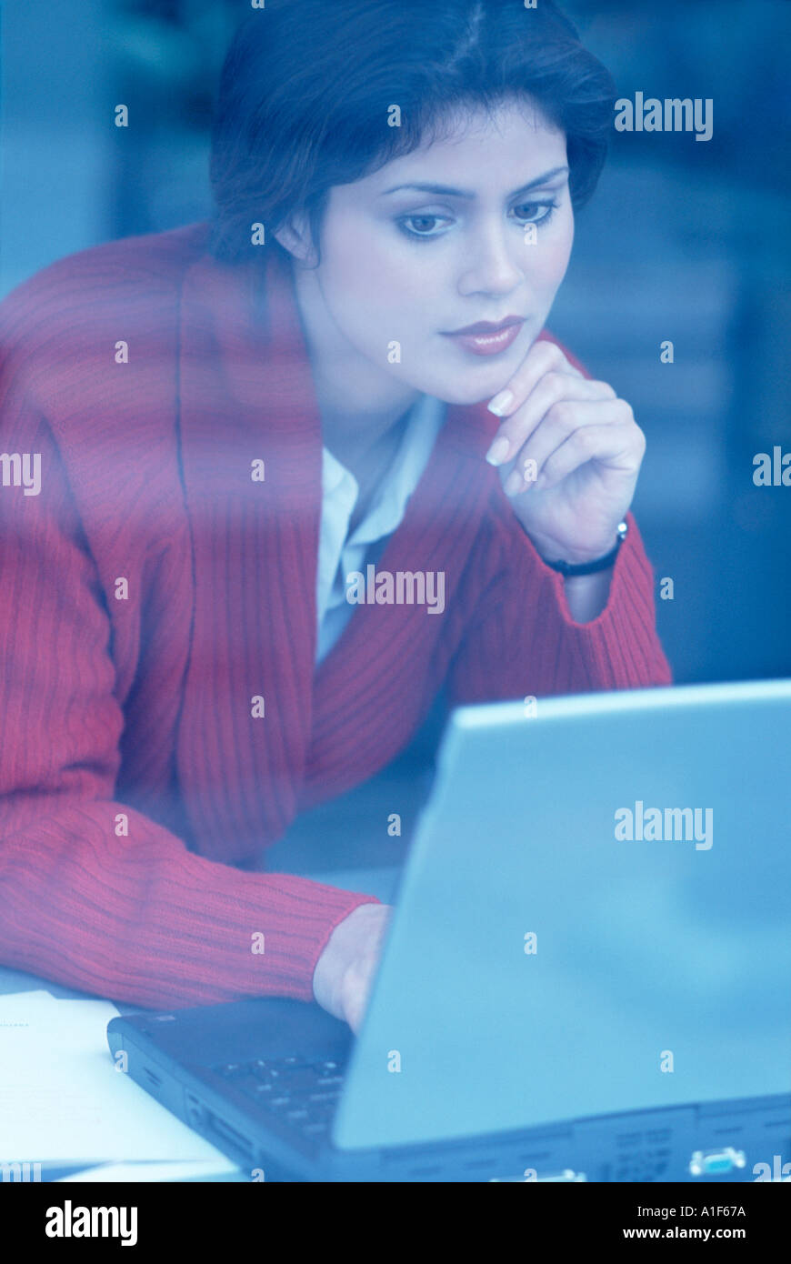 View of woman working on laptop through window Stock Photo