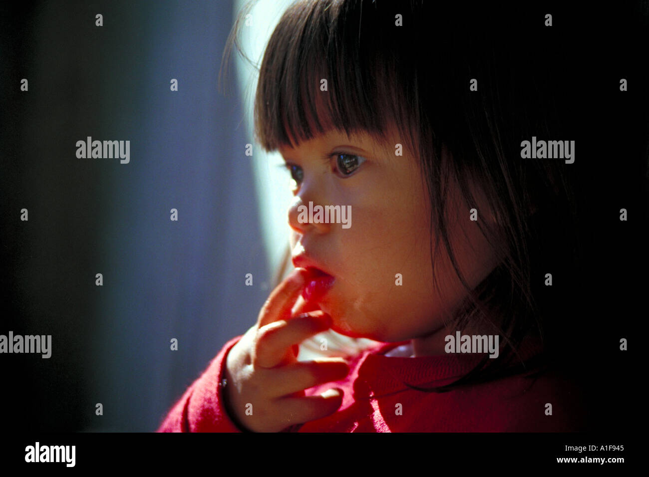 small asian girl with fingers in her mouth Stock Photo