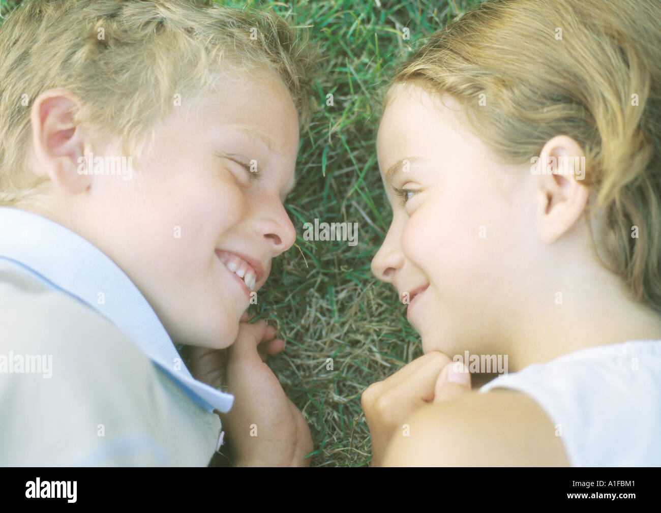 Boy and girl lying in grass, smiling Stock Photo