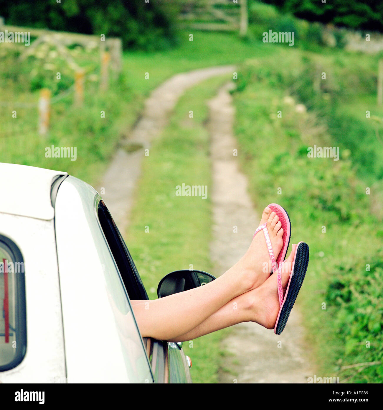 Woman's feet sticking out of a car window Stock Photo