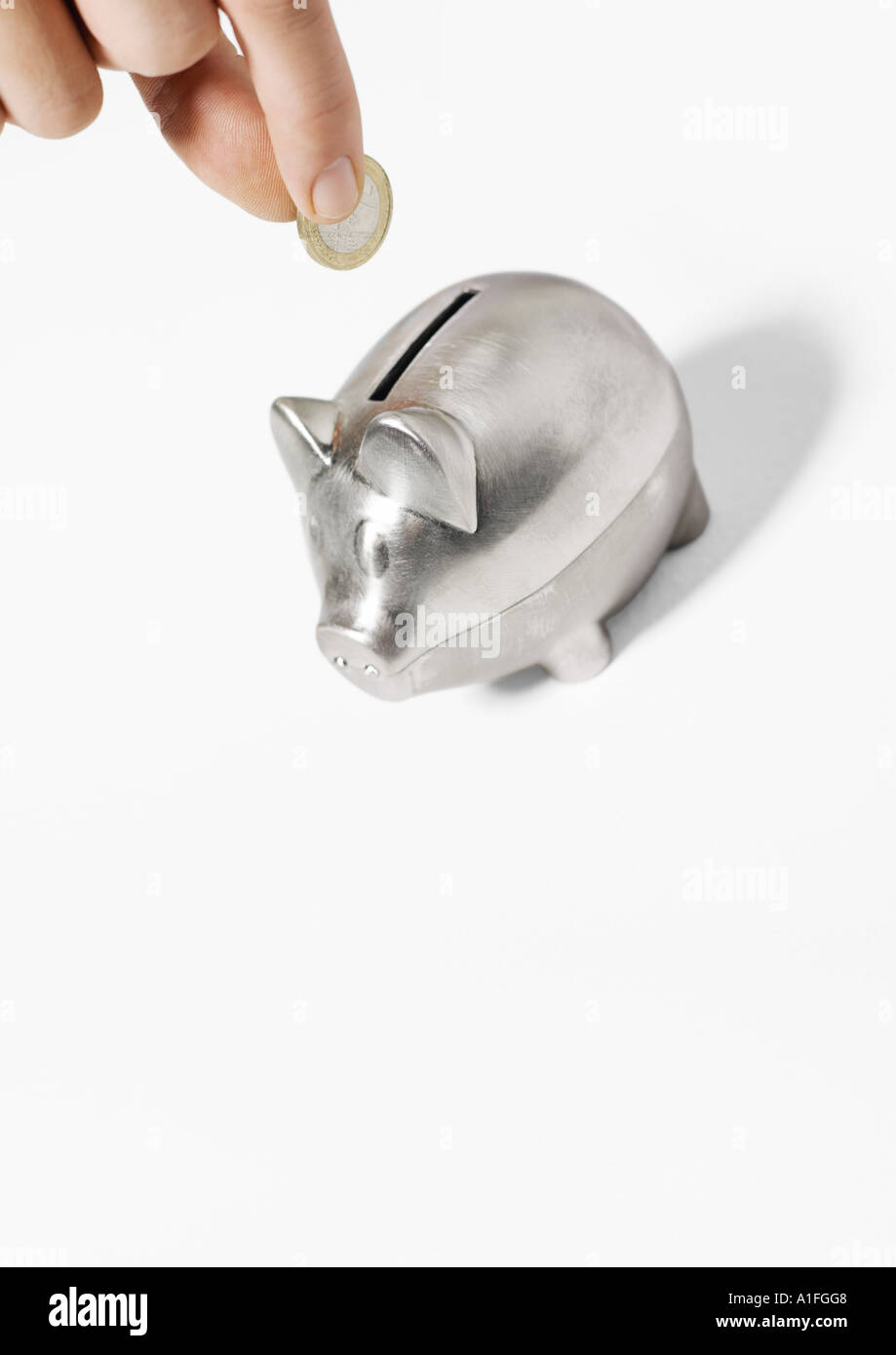 Hand inserting coin into piggy bank Stock Photo - Alamy