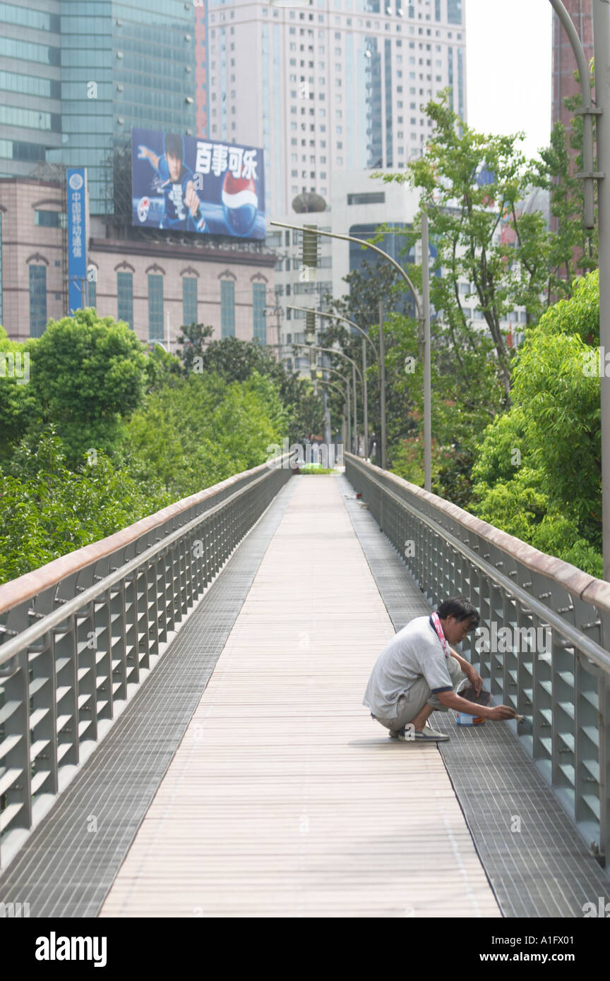 migrant worker painting bridge in xujiahui park shanghai china asia  Stock Photo