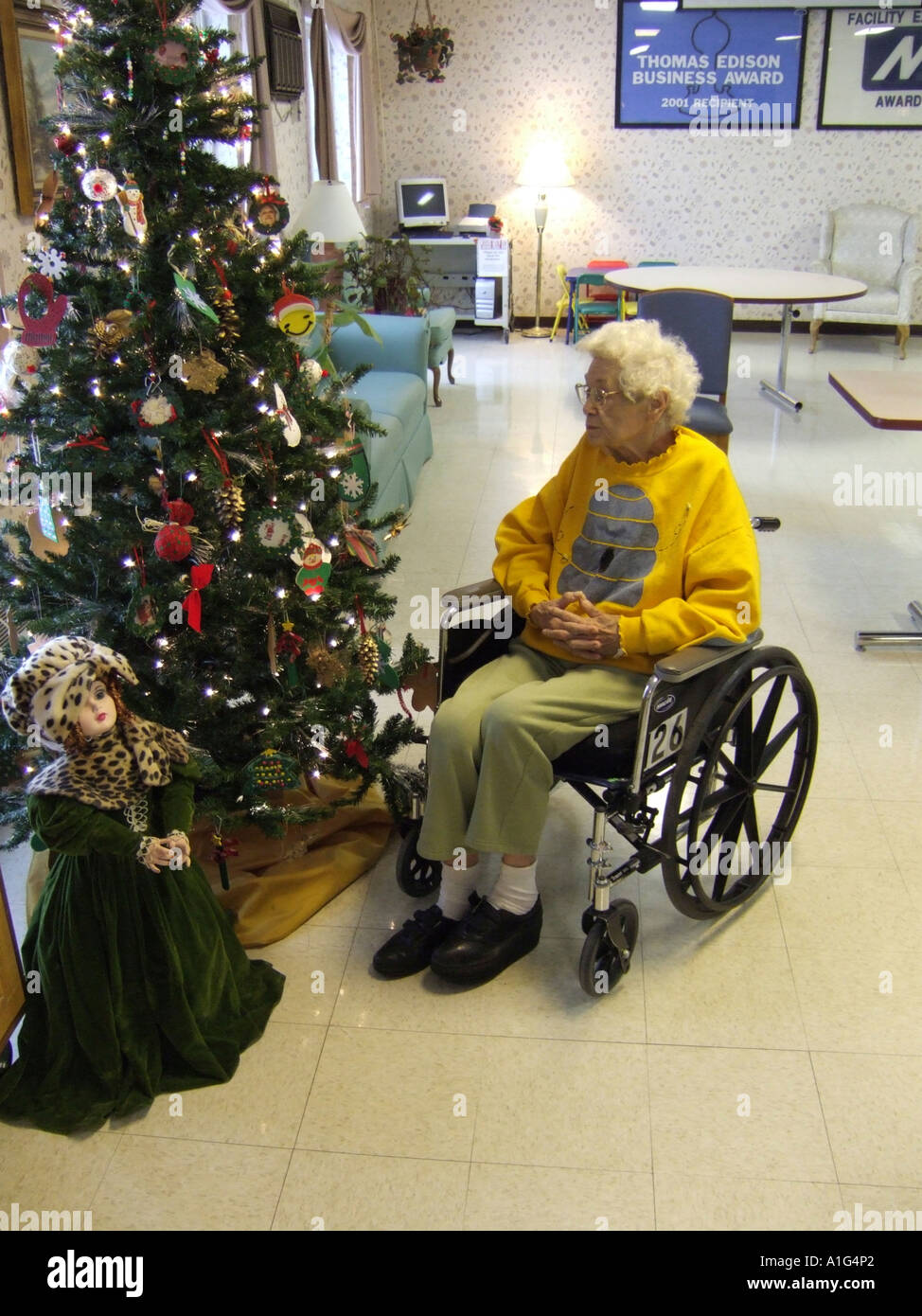 Senior female sits in a wheelchair next to a Christmas tree while rehabilitating from a fall in a nursing home Stock Photo