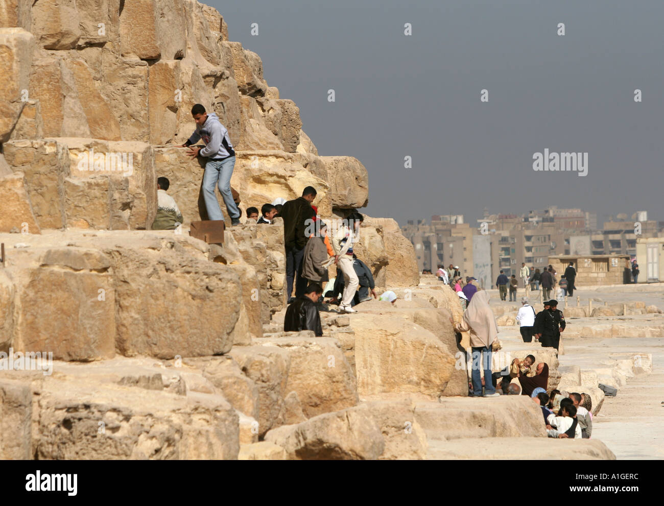 Young tourist climb on the great pyramids of Giza despite clear