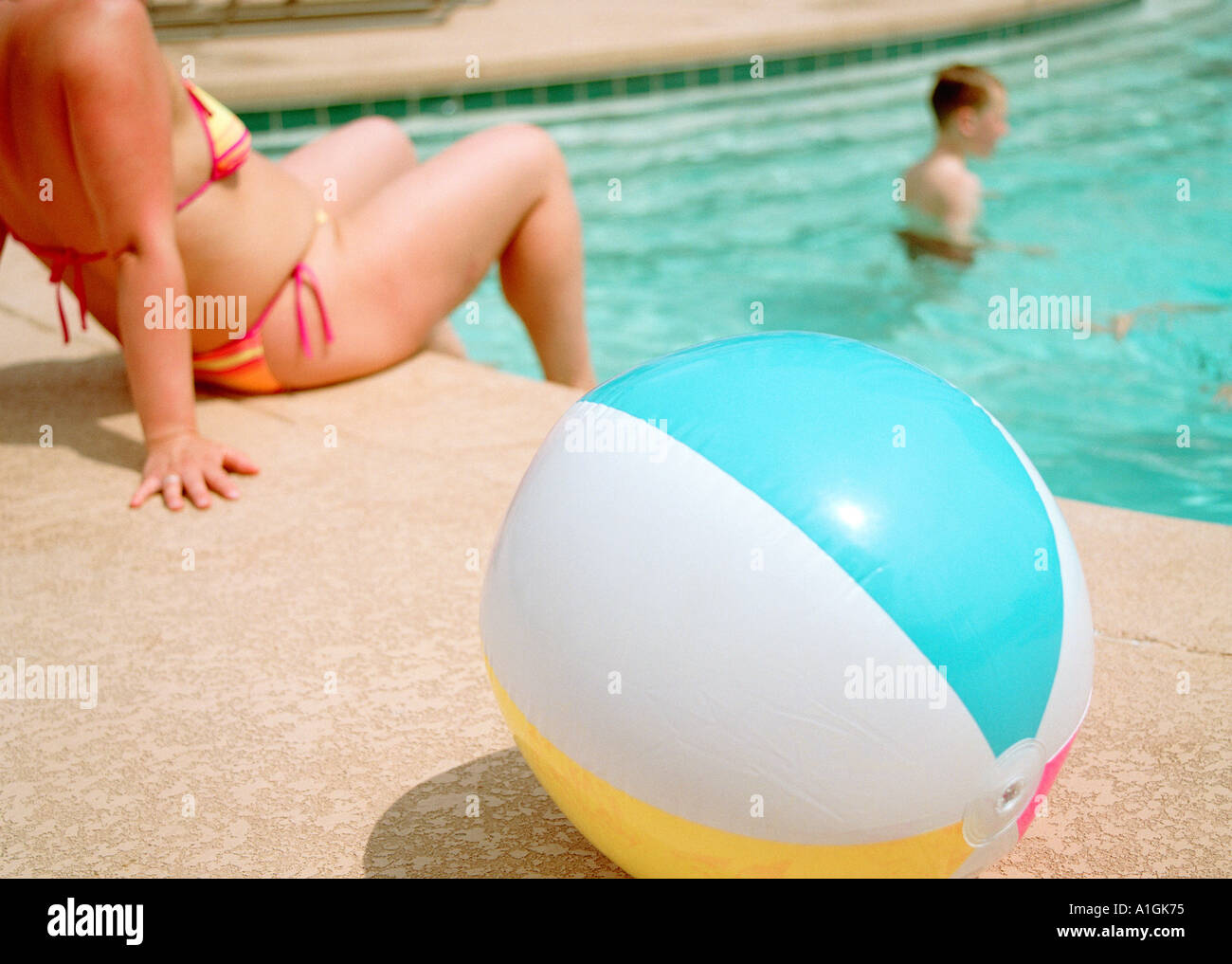 Beach  ball by the side of pool with lady in a bikini in the background California USA Stock Photo